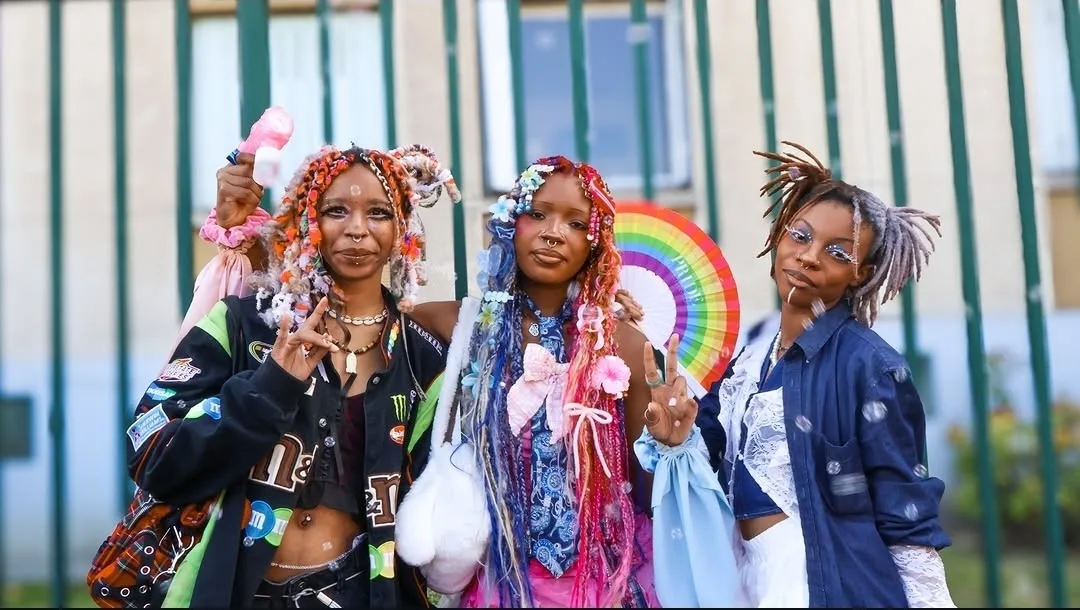 Trois jeunes personnes souriantes à la marche des fiertés